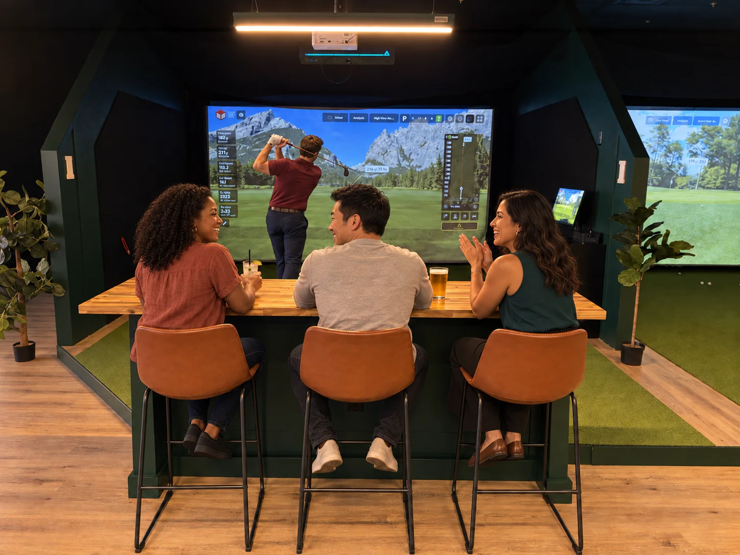 Golfer finishing a swing with friends seated behind the simulator bay